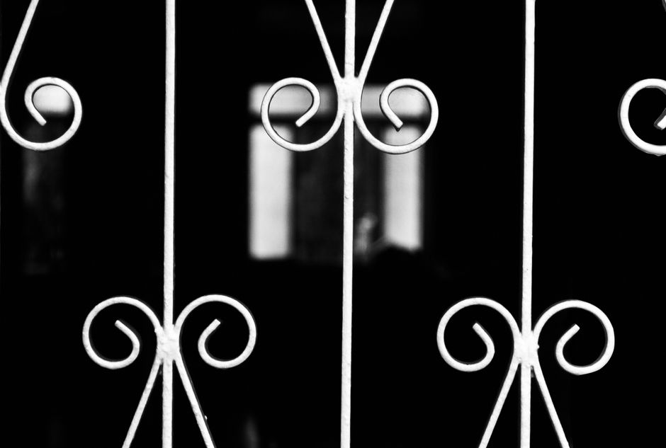 Close-up of a decorative wrought iron gate in black and white, showcasing intricate patterns.